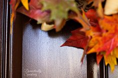 a close up of a door with autumn leaves on it and a clock in the background