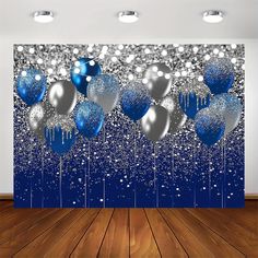 blue and silver balloons are hanging in front of a wall with white confetti