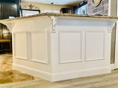 a kitchen island in the middle of a room with tile flooring and white cabinets