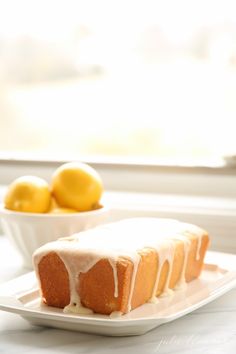 a loaf of lemon pound cake with icing on a plate next to some lemons