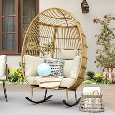 a rattan swing chair with cushions and pillows in front of a house