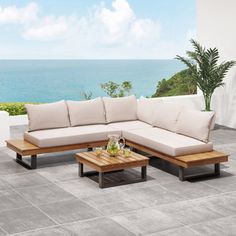 a couch and coffee table on a patio overlooking the ocean