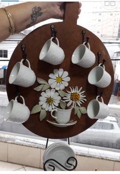 a person holding up a plate with coffee cups and flowers on it