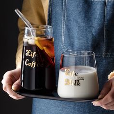 a person holding a tray with some drinks on it and a glass filled with milk