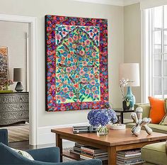 a living room filled with furniture and a colorful painting hanging on the wall over a coffee table