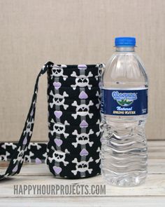 a bottle of water sitting next to a black and white bag with skulls on it