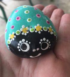 a hand holding a painted rock with flowers on it