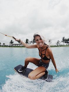 a woman on a surfboard in the water holding onto a rope and smiling at the camera