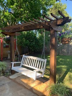 a white bench sitting under a wooden arbor