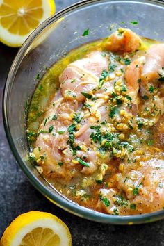 a glass bowl filled with chicken and lemons