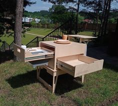 an outdoor grill made out of cardboard sitting in the grass next to a tree and stairs