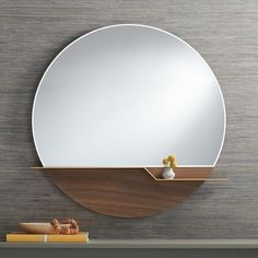 a round mirror sitting on top of a wooden shelf