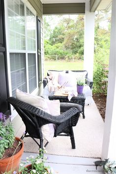 the porch is decorated with black wicker furniture and potted plants on the side