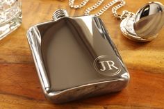 a silver flask with the initials j r on it sitting next to a crystal bottle