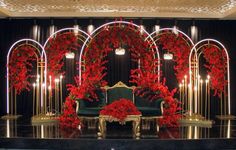 a stage set up with red flowers and gold accents for a wedding or special event