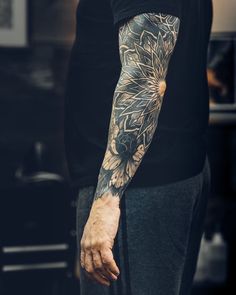 a man with a flower tattoo on his arm and hand is standing in the kitchen