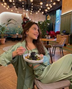 a woman sitting in a chair holding a plate of food