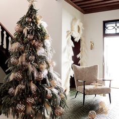 a decorated christmas tree sitting in the corner of a living room next to a chair