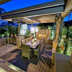 an outdoor kitchen and dining area is lit up at night with candles on the table