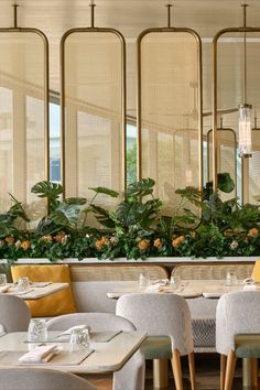 the interior of a restaurant with tables, chairs and plants on the windowsills