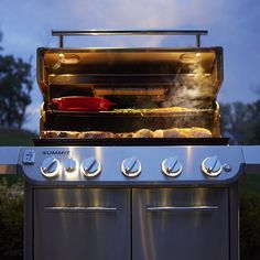 an outdoor grill with food cooking on it's burners and oven doors open