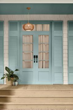 a blue front door with two planters on the steps and one light hanging over it