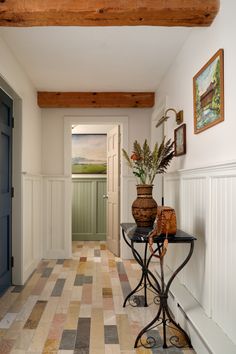 a hallway with a table and vases on it