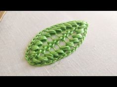 a crocheted piece of green yarn sitting on top of a white table cloth