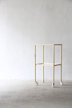 a white cart sitting on top of a cement floor next to a wall with wheels