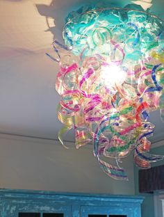 a colorful chandelier hanging from the ceiling in a room with blue shutters