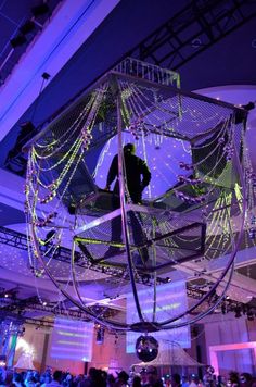 a man standing on top of a net suspended from the ceiling in front of a crowd