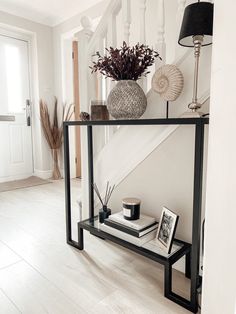 a black and white console table with vases on it in front of the stairs