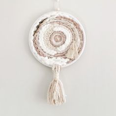 a white and brown circular wall hanging with tassels