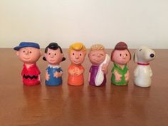 a group of small toy figurines sitting on top of a wooden table next to a white wall