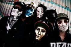 five people with face paint and masks posing for a photo in front of a wall