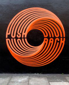 an orange sign that says push back on the side of a building in front of a black wall