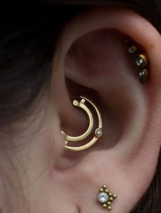 an ear with three different types of piercings on it's sides and one is in the shape of a crescent