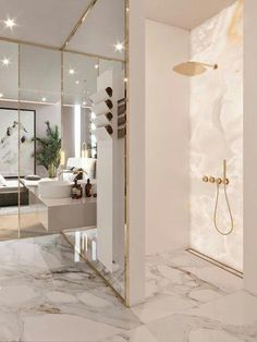 a bathroom with marble flooring and gold trim around the shower head, mirror on the wall