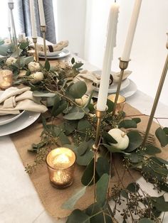 the table is set with candles, greenery and other things to decorate on it