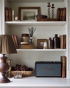 the shelves are filled with books, candles and other decorative items such as pine cones