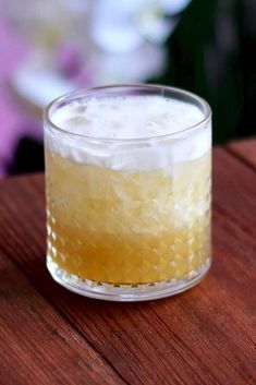 a glass filled with liquid sitting on top of a wooden table