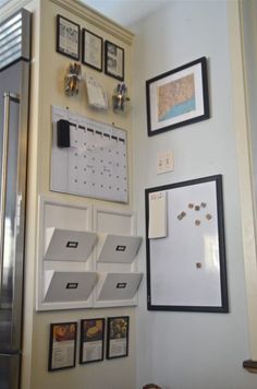 a kitchen wall with pictures, calendars and magnets hanging on the wall next to a refrigerator