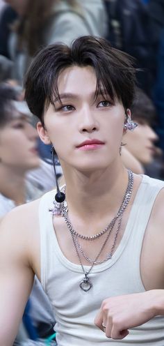 a young man in a white tank top and chain necklace