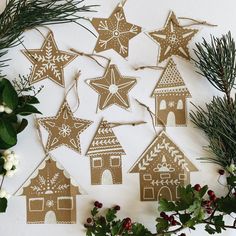 christmas decorations made out of brown paper and decorated with white snowflakes, holly branches and star shaped gingerbread houses