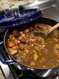 a large pot filled with food sitting on top of a stove next to a wooden spoon