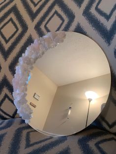 there is a mirror that has flowers on the bottom half of it, and a lamp in the middle