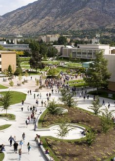 an aerial view of a city with mountains in the back ground and people walking around