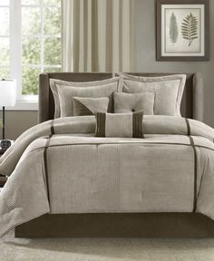 a bed in a bedroom with beige comforter and pillows