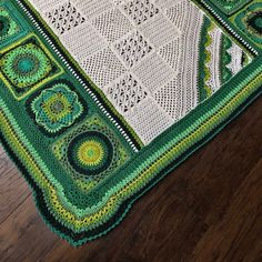 a green and white crocheted afghan on a wooden floor