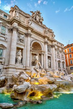 an ornate building with statues and fountains in front of the entrance to it, surrounded by blue water